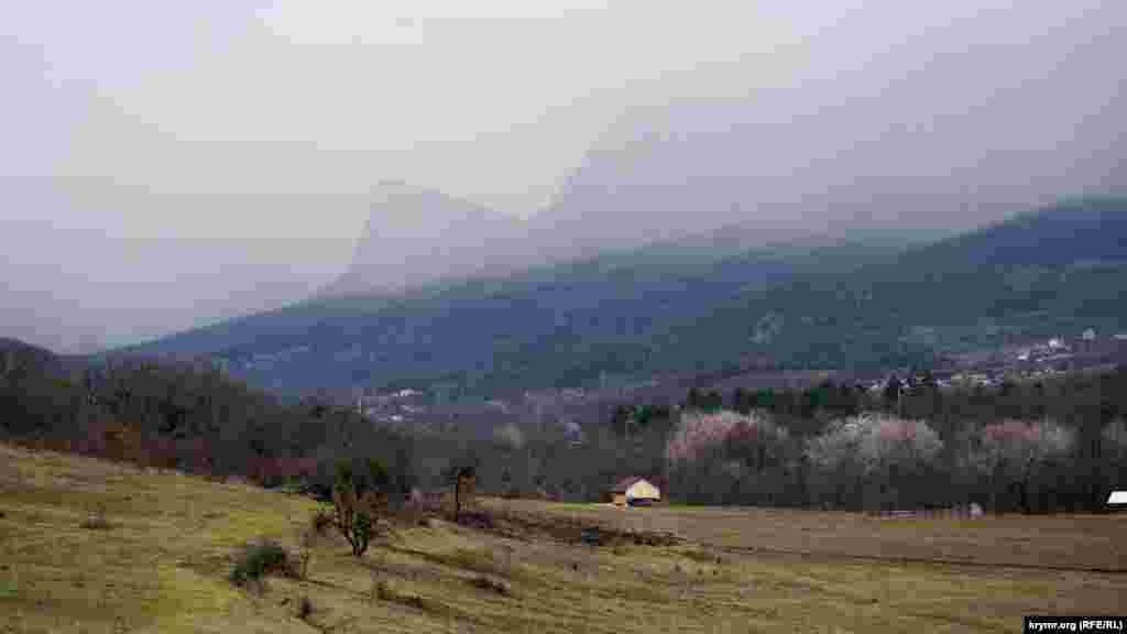 Дрібний дощ на тлі Головної гряди Кримських гір. Майже в центрі &ndash; затуманена гора Орлиний Заліт (Седам-Кая). Ліворуч видніються будівлі села Соколине Бахчисарайського району
