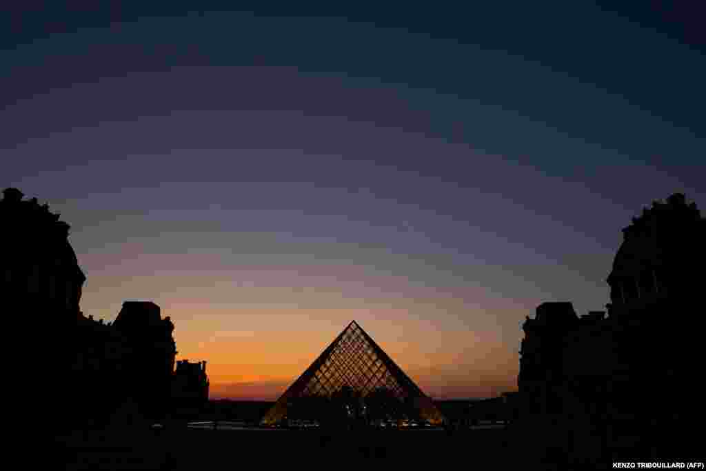 FRANCE - (FILES) In this file photo taken on March 21, 2019 the sun sets behind the Louvre Pyramid, designed by Chinese-American architect I.M. Pei, in Paris