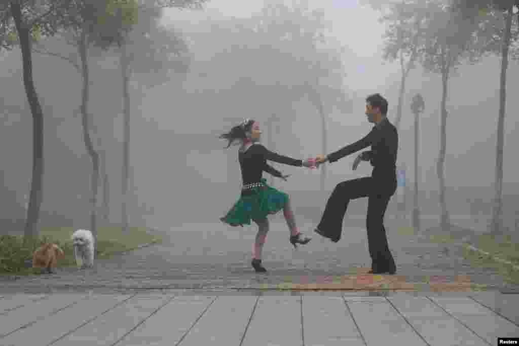 A man and woman dance in a park on a foggy day in Huai'an, China. (Reuters)