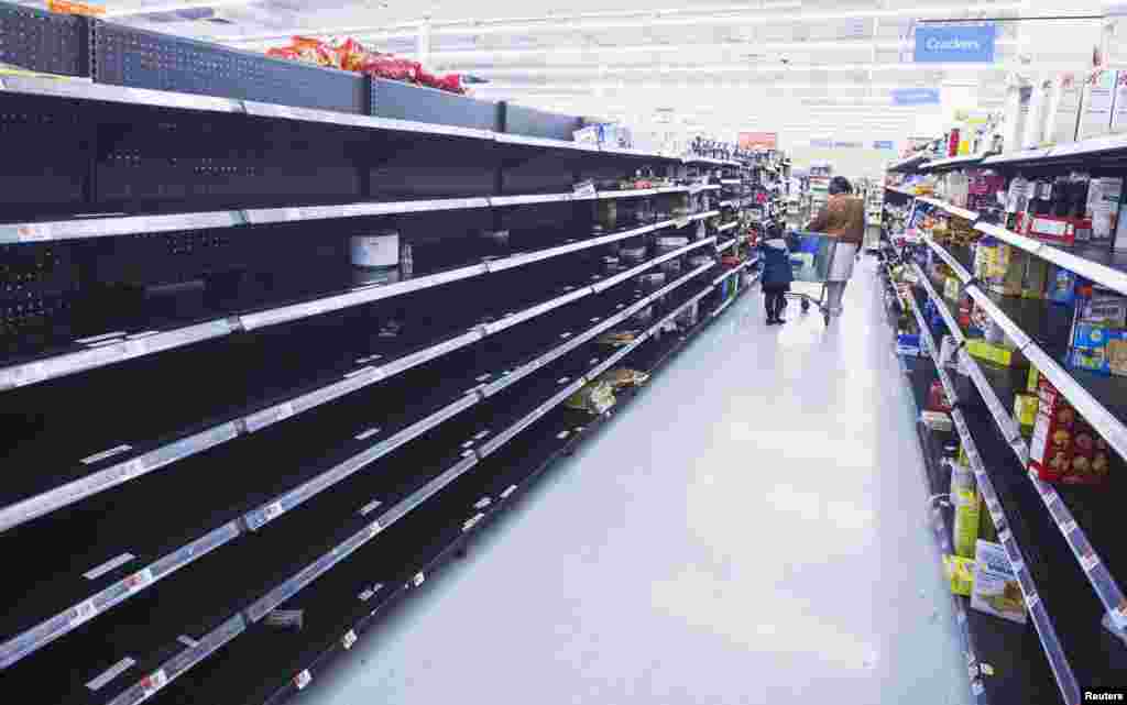 A woman and child walk through an aisle, emptied in preparation for Hurricane Sandy, in a Wal-Mart store in Riverhead, New York. 