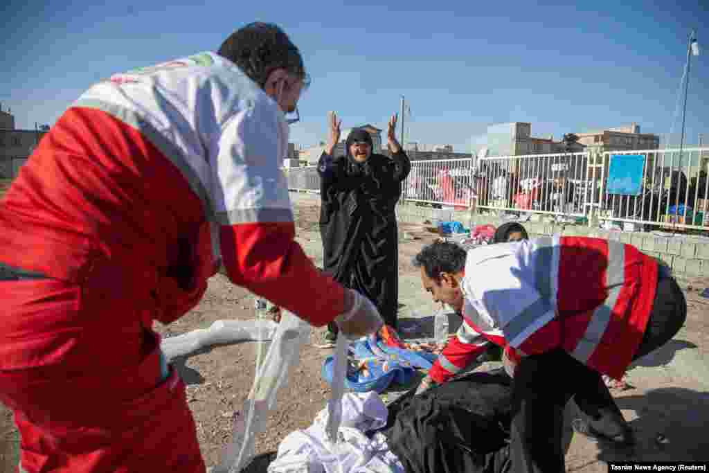 A woman reacts as medics cover dead bodies in Sarpol-e Zahab.