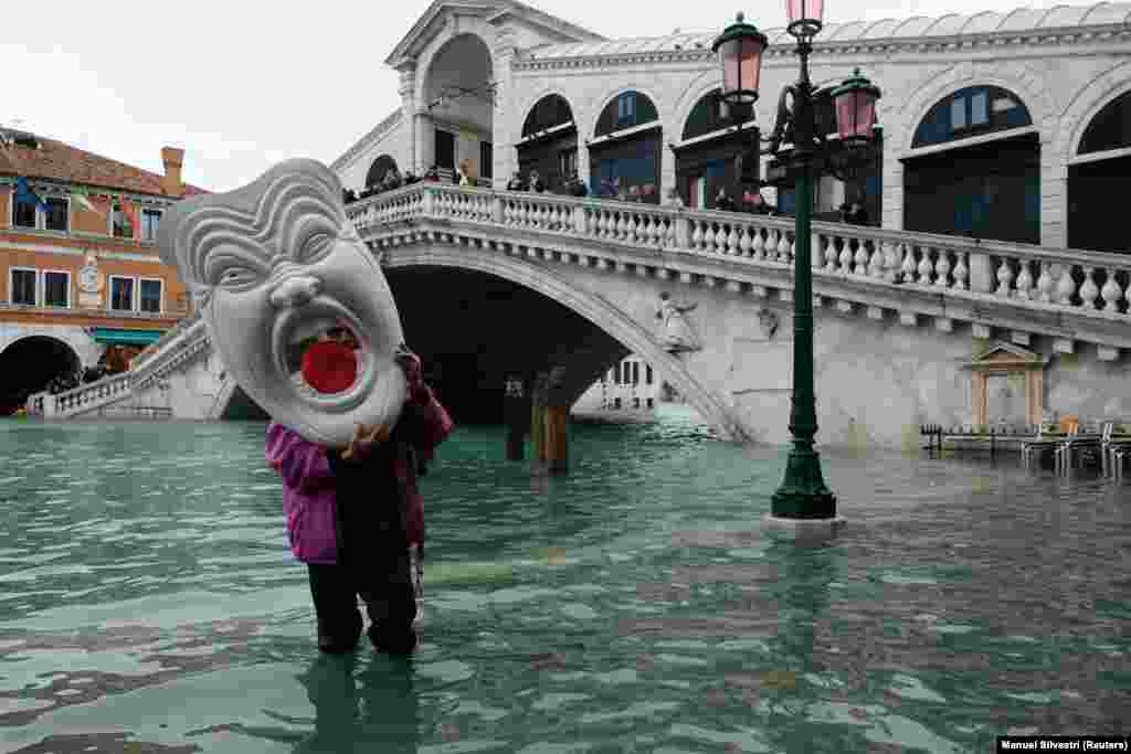 Чоловік із маскою ходить по затопленій вулиці у Венеції. Щорічну сезонну повінь мешканці міста називають &laquo;високою водою&raquo; (acqua alta), але цьогоріч вона сягнула небувалих розмірів&nbsp;