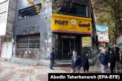 Iranians walk past next to a post office that was burned and destroyed during the protests in the city of Shahriar, Alborz province, November 20, 2019