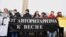 Тәуелсіздік монументі алдында плакат көтеріп тұрған Oyan, Qazaqstan жастар қозғалысы белсенділері. Алматы, 16 желтоқсан 2019 жыл.