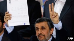 Former Iranian President Mahmud Ahmadinejad flashes the victory sign at the Interior Ministry's election headquarters after registering to run for president.