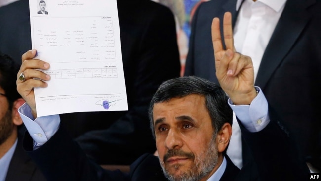 Former Iranian President Mahmud Ahmadinejad flashes the victory sign at the Interior Ministry's election headquarters after registering to run for president.