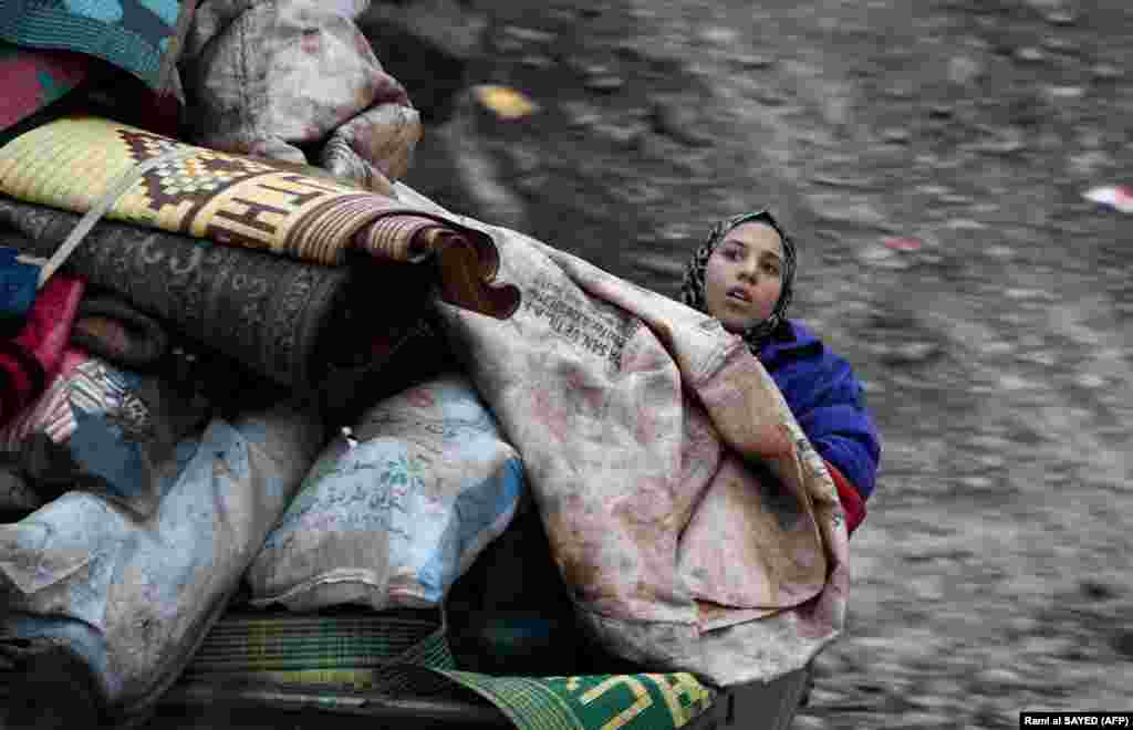 A Syrian girl rides in the back of a truck as people displaced from Idlib Province travel in vehicles loaded with furniture and other belongings as they flee from advancing government forces. (AFP/Rami al-Sayed)