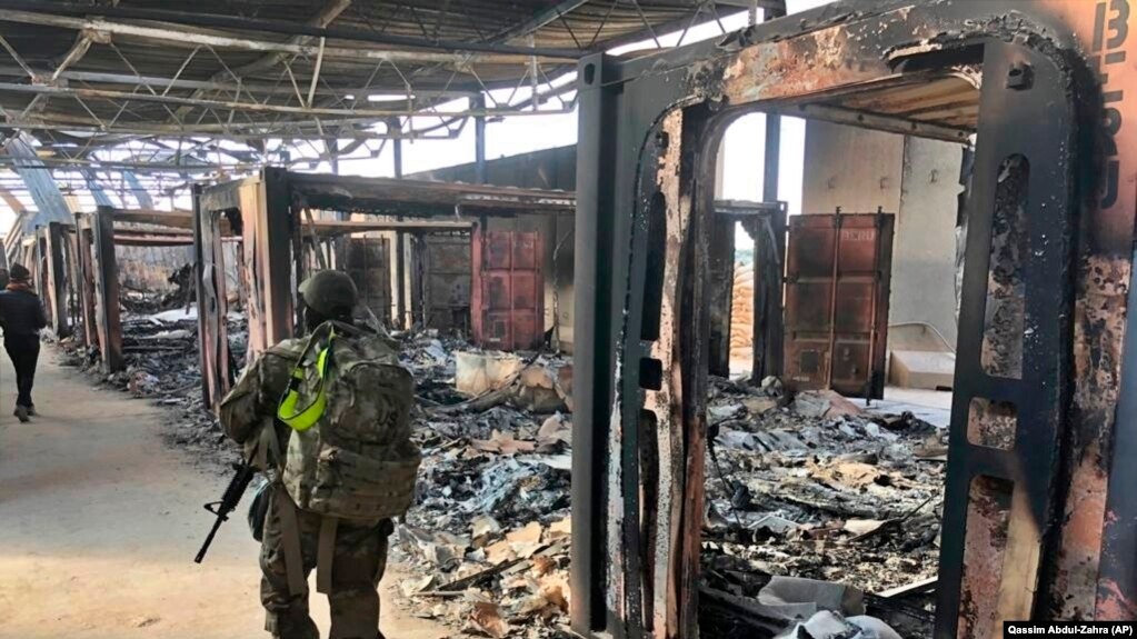 U.S. soldiers on January 13 walk past the site of where Iran bombed the Ain Al-Asad air base in Iraq. 