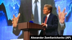 Purtătorul de cuvând Dmitry Peskov, bottom, looks on as Russian President Vladimir Putin speaks via video call during a news conference in Moscow, December 17, 2020