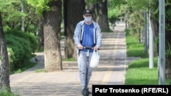 Маска таққан ер адам самокат айдап барады. Алматы, 25 сәуір 2020 жыл. 