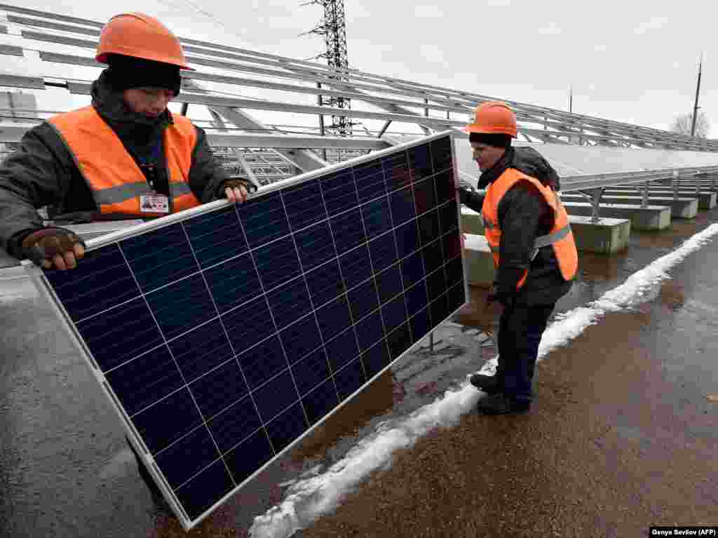 Workers wrestle one of the new Chernobyl project&#39;s 3,800 solar panels into position. The Ukrainian-German company behind the project told AFP on January 10 that the solar plant will generate enough electricity to power &quot;a large village,&quot; or around 2,000 apartments. &nbsp;