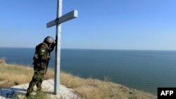 Украинский пограничник возле креста, установленного на берегу Азовского моря вблизи Мариуполя, 2 октября 2014 года.