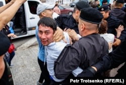 Полицейские задерживают мужчину во время митинга в Алматы, 9 июня 2019 года.