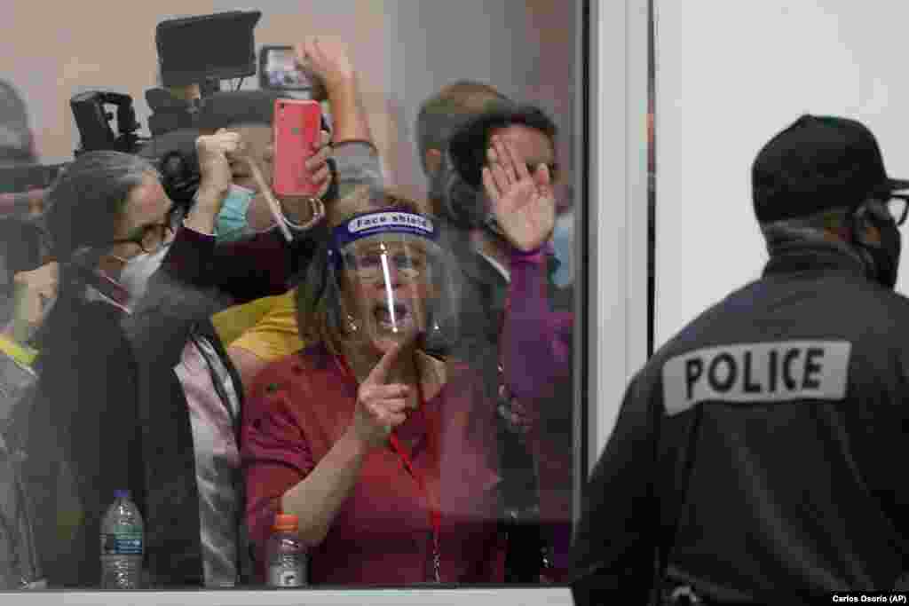Election challengers yell as they look through the windows of the central counting board as police were helping to keep additional challengers from entering due to overcrowding, Wednesday, Nov. 4, 2020, in Detroit.