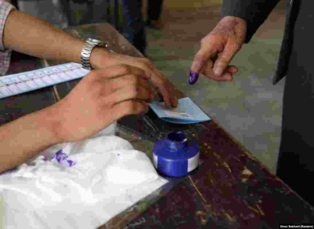 An election official assists an Afghan man at a polling station in Kabul