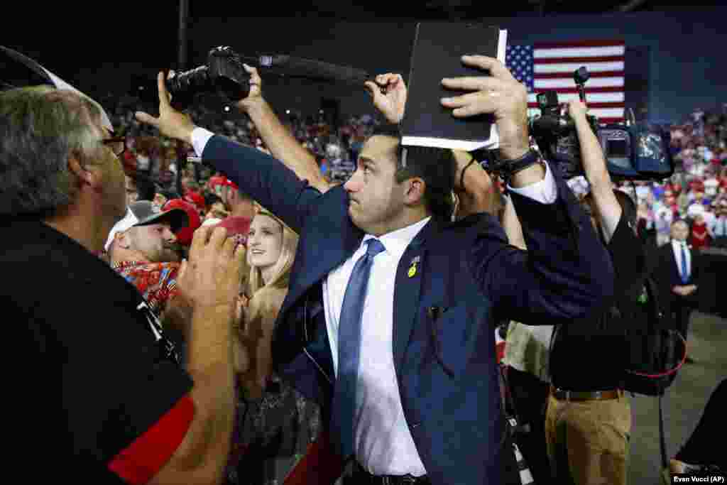 A volunteer member of the advance team for U.S. President Donald Trump blocks a camera with his hand as a photojournalist attempts to take a photo of a protester during a campaign rally in Evansville, Indiana, on August 30. (AP/Evan Vucci)