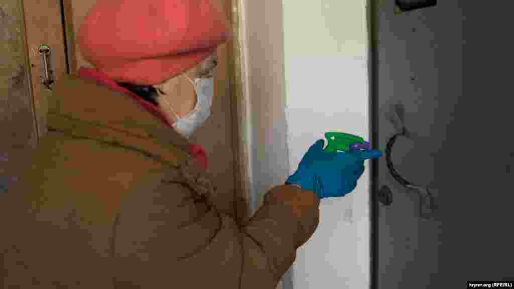 Працівниця ЖЕКу дезінфікує дверні ручки в під&#39;їзді багатоповерхівки одного зі спальних районів кримської столиці