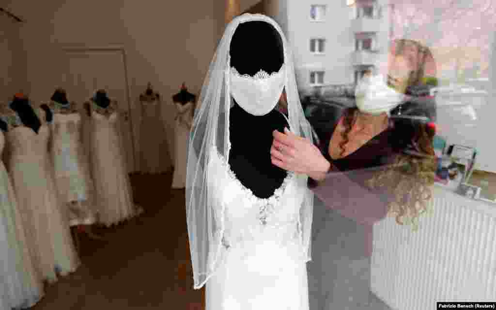 Fashion designer Friederike Jorzig adjusts a matrimonial​ mask for wedding dresses in her Berlin shop.