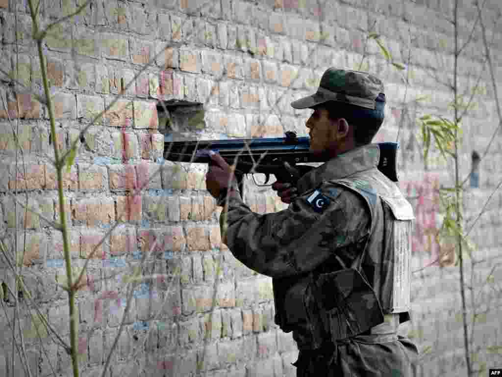 A soldier takes up a position outside a besieged mosque in Rawalpindi, Pakistan. - Three suicide bombers fired on worshippers then blew themselves up at a mosque near Pakistan's military headquarters after Friday Prayers on December 4, killing 40 people, including many army officials. Photo by Nicolas Asfouri for AFP