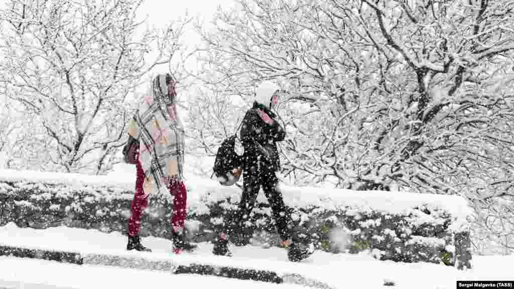 Девушки спешат по делам, укутавшись от снега в Гаспре