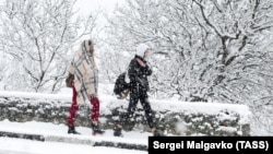 Люди во время снегопада на одной из дорог в крымском поселке Гаспра, 15 января 2021 года
