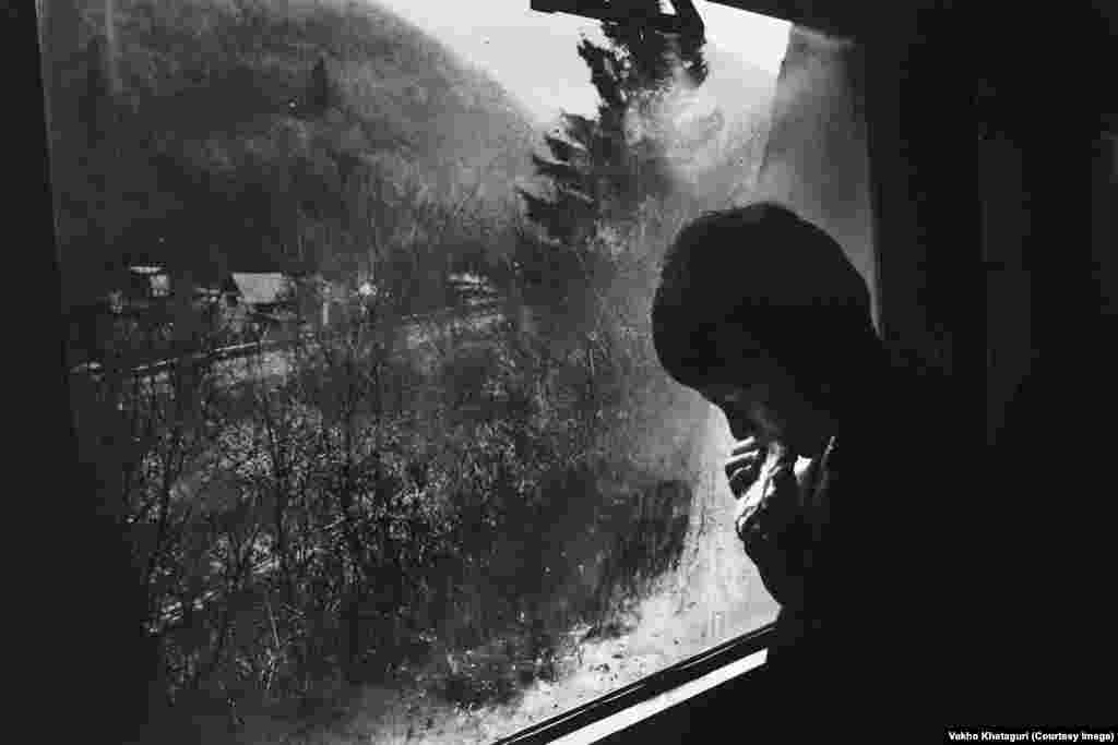 A boy stands at the window of a train, as it passes through the Borjomi Gorge.