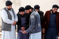 Afghan Sikh men mourn during funeral for the victims who were killed during a March 25 attack on a Sikh gurdwara in Kabul.