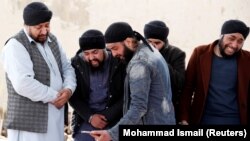 FILE: Afghan Sikh men mourn during funeral for the victims who were killed during a March 25 attack on a Sikh Gurdwara in Kabul.