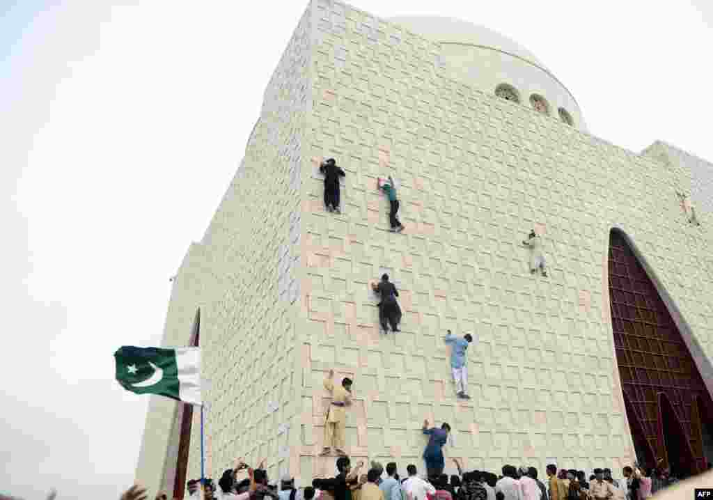 Pakistani youths climb the facade of the mausoleum in Karachi of Muhammad Ali Jinnah, who was the founding father of Pakistan, as they celebrate the country&#39;s 66th Independence Day. (AFP/Rizwan Tabassum)