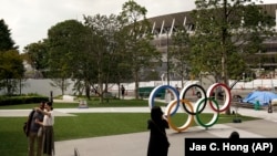 Олимпийские кольца рядом с новым стадионом, местом проведения церемоний открытия и закрытия Олимпийских игр в Токио.