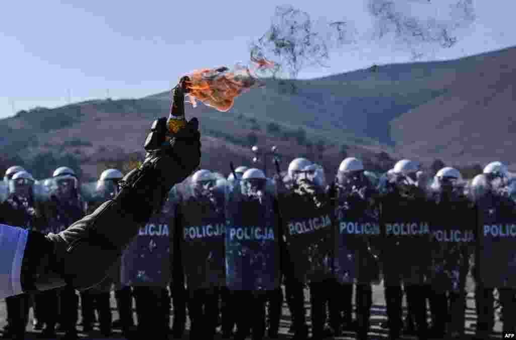 A riot policeman holds a Molotov cocktail as police and soldiers serving in the NATO-led peacekeeping force (KFOR) take part in a crowd and riot-control exercise near the village of Vrelo, Serbia. (AFP/Armend Nimani)