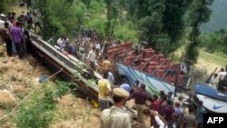 Locals and policemen gather around the bus as they rescue injured passengers from the damaged bus near the village Maroti, in Udhampur district of Jammu and Kashmir on May 11.