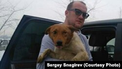 Сергей Снегирев көзі зақымданған итті емханаға апара жатыр.