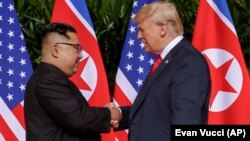 АҚШ президенті Дональд Трамп Солтүстік Корея лидері Ким Чен Ынмен қол асылып тұр. Сингапур, 12 маусым 2018 жыл.