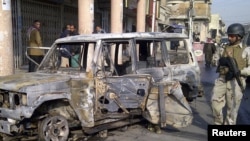 A soldier stands guard near a burnt vehicle after a bomb attack in Alawi district in central Baghdad on December 22.