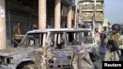 Iraq -- A soldier stands guard near a burnt vehicle after a bomb attack in Alawi district in central Baghdad, 22Dec2011