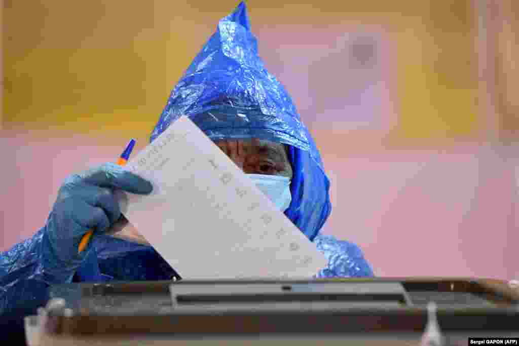 A woman wearing a face mask and gloves casts her ballot at a polling station during Moldova's presidential election in Chisinau on November 1. (AFP/Sergei Gapon) 