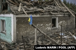 Український прапор перед частково зруйнованим будинком в місті Ірпіні на Київщині, 16 червня 2022 року