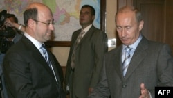 Vladimir Putin (R) shakes hands with Russian politician Aleksandr Babakov (file photo)