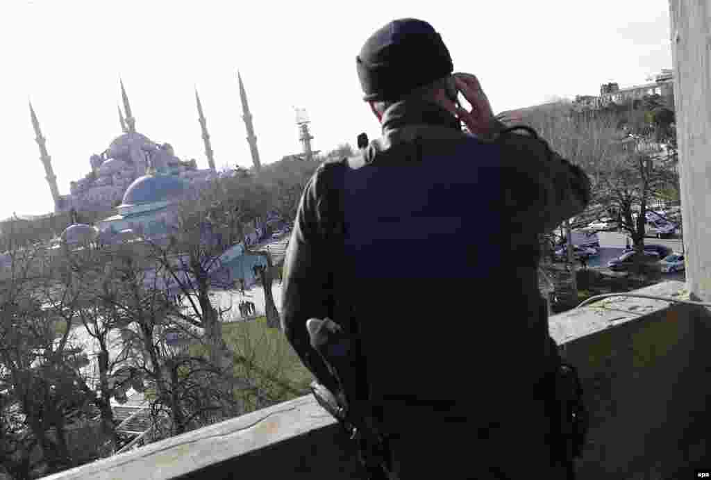 A member of a Turkish SWAT team stands guard on a nearby building.