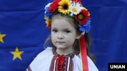Девочка в национальном костюме на фоне флага Евросоюза во время празднования Дня независимости Украины в Киеве, 2014 год