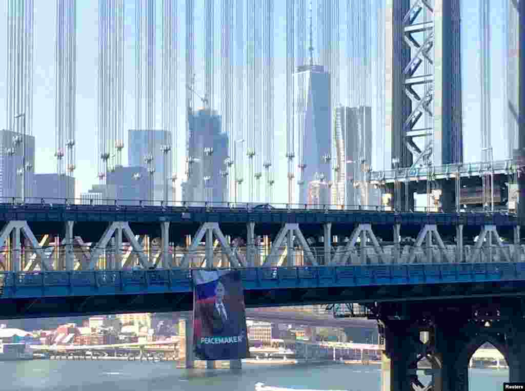 A banner with an image of Russian President Vladimir Putin in front of Russian and Syrian flags hangs from the Manhattan Bridge in New York City on October 7, Putin's birthday. Police removed the banner shortly after it was unfurled and are investigating the incident. (Reuters/Kathryn Peters)