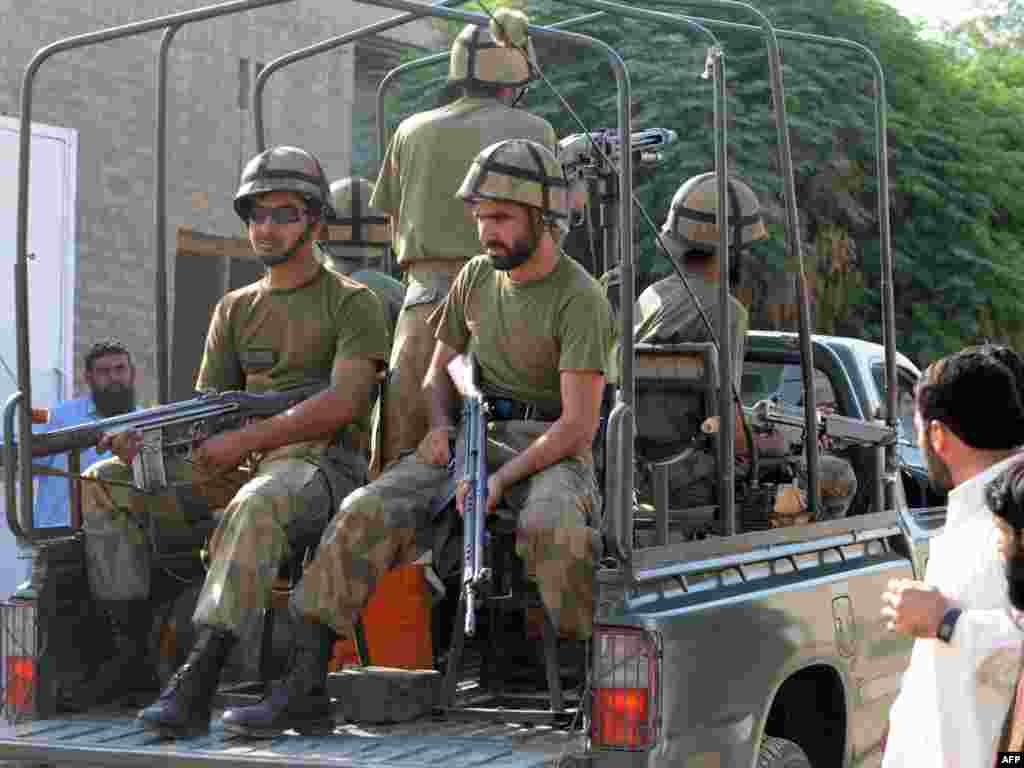 Pakistan -- Pakistani troops patrol beside internally displaced civilians fleeing from military operations against Taliban militants in South Waziristan, Dera Ismail Khan, 21Oct2009 - PAKISTAN, Dera Ismail Khan : Pakistani troops patrol beside internally displaced civilians fleeing from military operations against Taliban militants in South Waziristan, as they stand in line for their registration in Dera Ismail Khan on October 21, 2009. Pakistani troops and Taliban fighters were locked in fierce clashes in a major offensive that officials said had killed more than 100 people and uprooted 120,000. Pakistan faces its toughest military test yet against the rebels in waging the ground assault in South Waziristan, part of a lawless tribal belt where Al-Qaeda and Taliban networks are allegedly plotting attacks on the West.