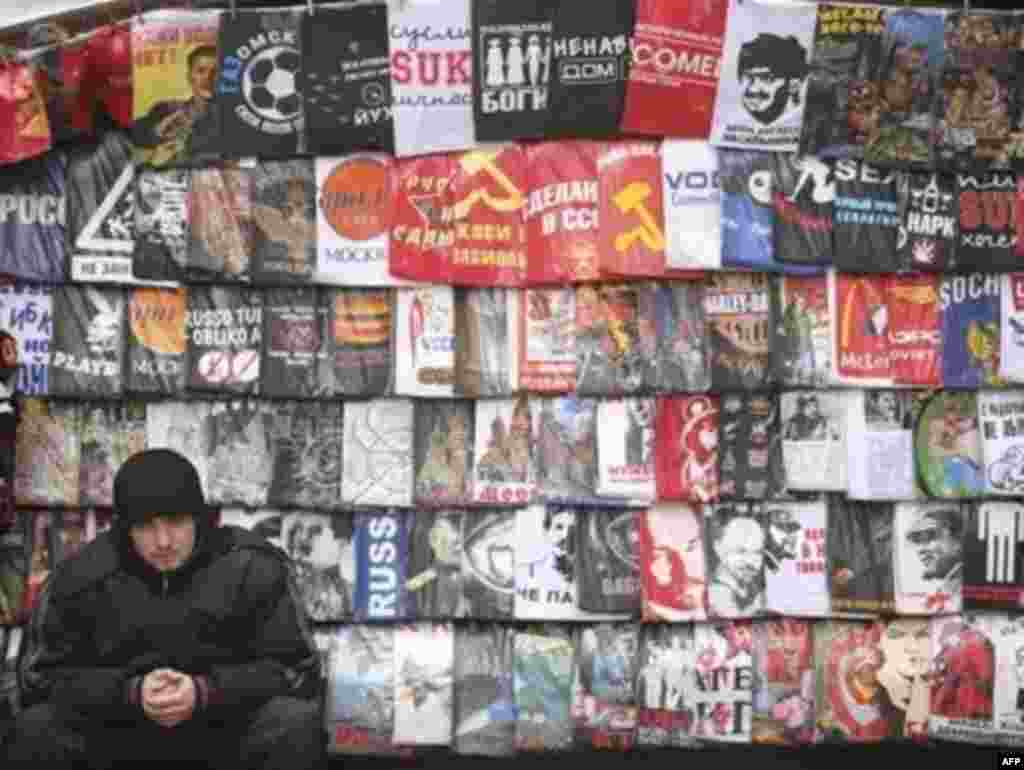 A Moscow vendor flanked by Soviet-themed memorabilia and T-shirts - Both Russians and foreign tourists are in the market for memorabilia glorifying the symbols of the communist past, like these T-shirts on sale at a Moscow street stall.