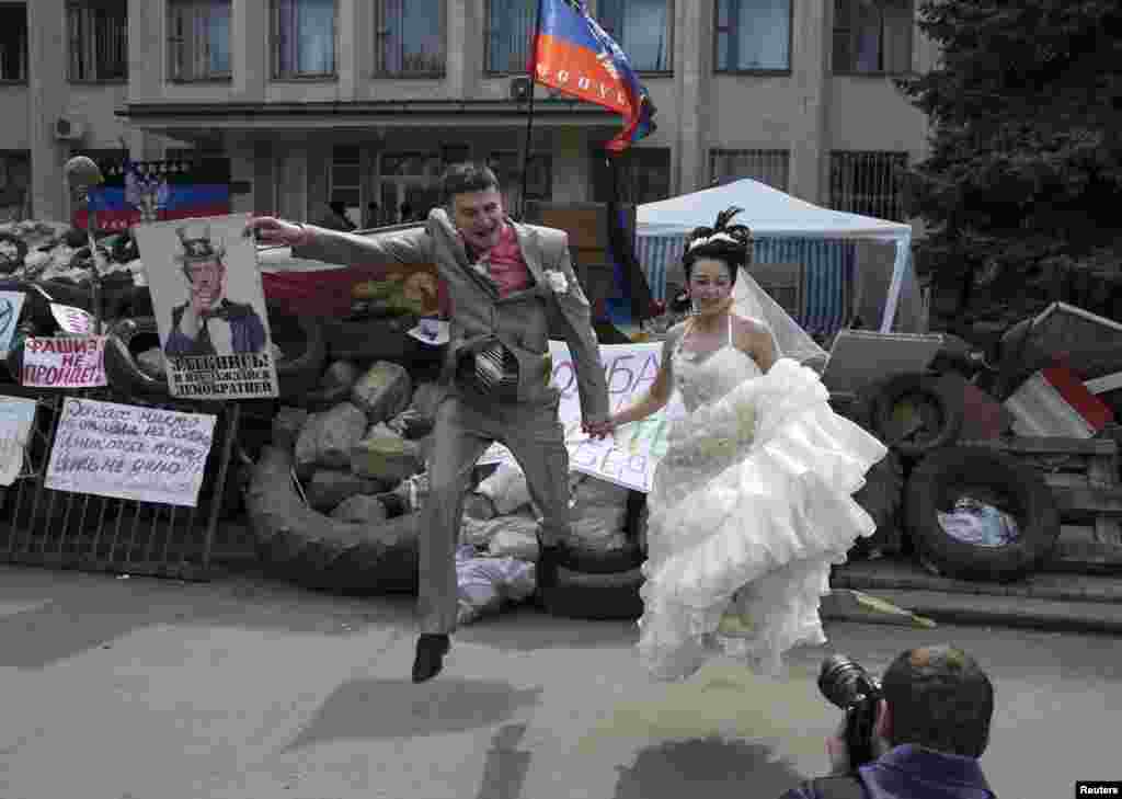 A bride and groom jump for a picture in front of barricades outside a regional government building seized by pro-Russian gunmen in the eastern Ukrainian city of Kramatorsk. (Reuters/Baz Ratner)