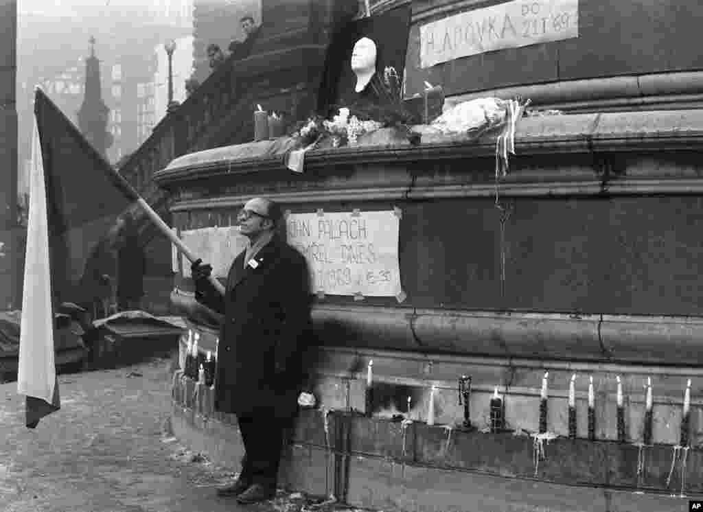 A demonstrator holds a Czechoslovak flag near a makeshift memorial for Palach.