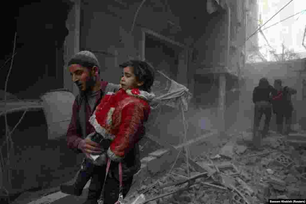 SYRIA -- A man holds a child after an airstrike in the besieged town of Douma, Eastern Ghouta, Damascus, Syria February 7, 2018