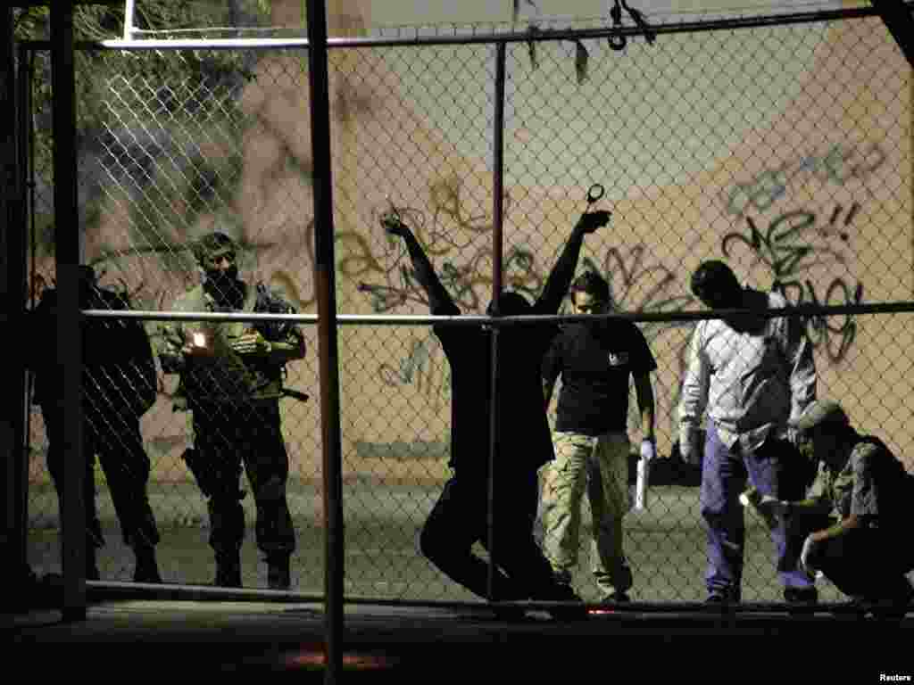 Military and forensic experts inspect the body of a man who was killed outside a nightclub in the border city of Ciudad Juarez August 31, 2009. A man was handcuffed to a fence and shot several times by drug hitmen outside a nightclub, according to local media. The assailants also left a warning message, known as "narco mensaje", at the site of the shooting. Picture taken August 31, 2009. REUTERS/Alejandro Bringas 