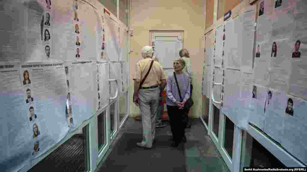 People examine the lists of political parties at a polling station in Kyiv. (RFE/RL/Serhii Nuzhnenko)