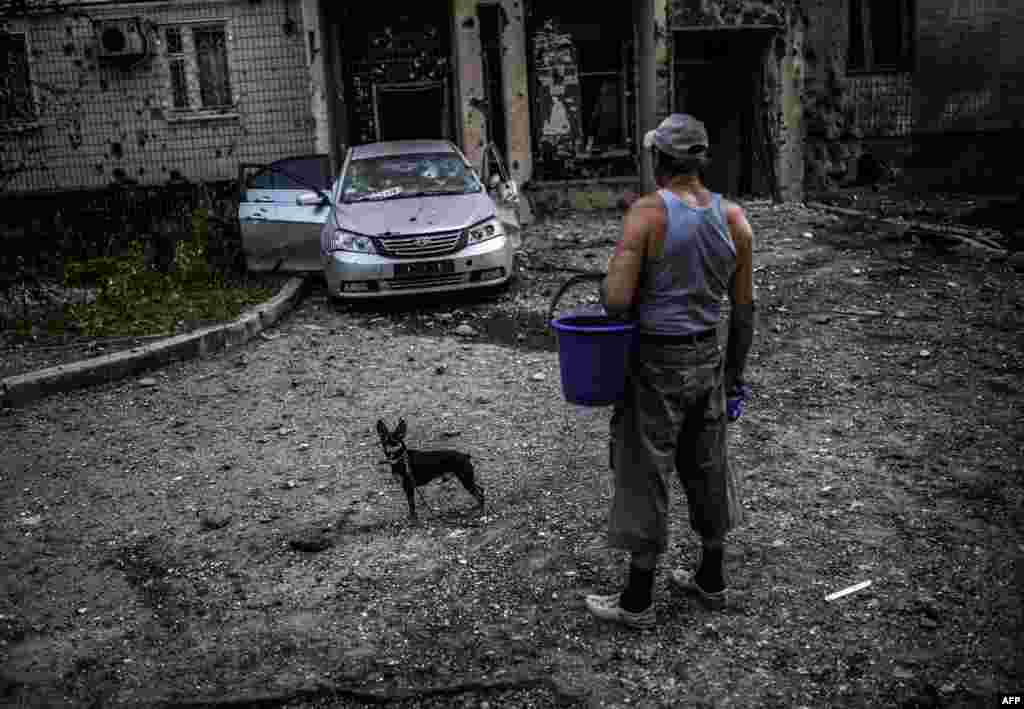 A man with his dog looks at a damaged area after shelling in Donetsk, eastern Ukraine on July 29. (AFP/Bulent Kilic)